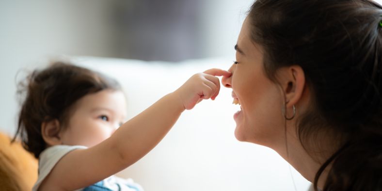 Mother smiling as her baby reaches for her nose