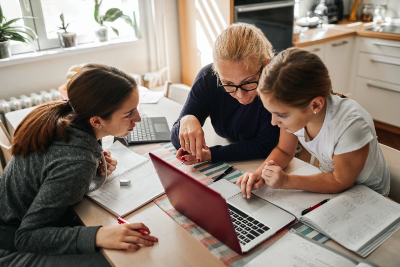 Single mother in the kitchen with daughters helping with homework