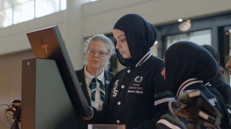 Hospitality teacher and students looking at computer monitor