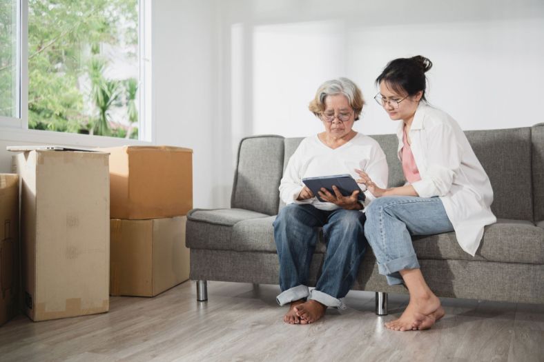 An older woman and her daughter look at a screen surrounded by boxes