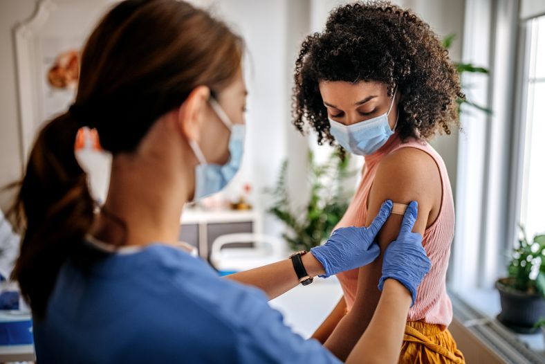 Bandage is applied to woman's arm after vaccination