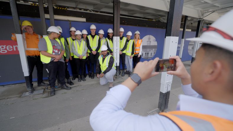 Group of high school students in construction gear posing in front of camera