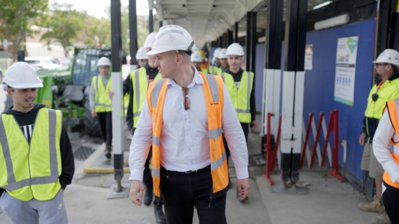 Group of high school students in construction gear walking on footpath