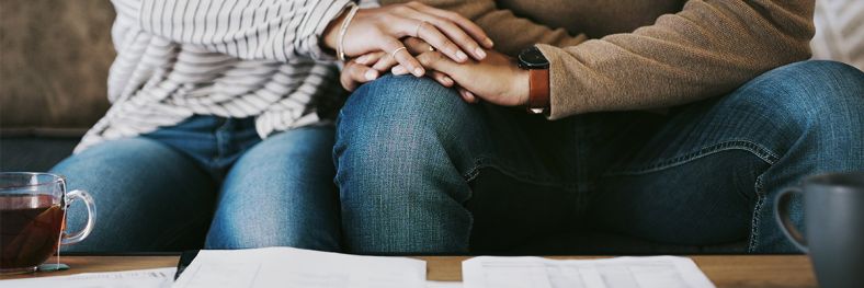 Couple holding hands while looking at table with papers on it