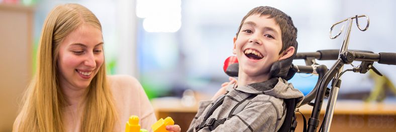 young boy in wheelchair smiling at camera