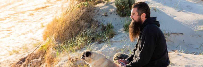 Man watching sunset on beach with dog