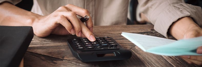 Person holding paper while using calculator 