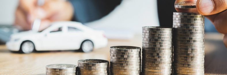 Image of coins stacked like a graph with a model car in background