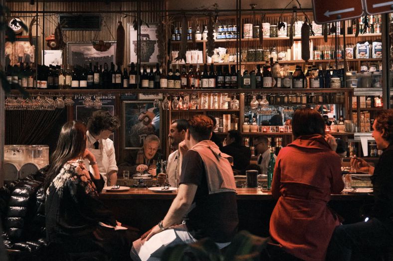 Group of people sitting at a bar with their backs facing the camera