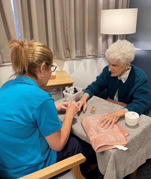 Alicia Madden paints the nails of a female aged care resident at Murrumburrah-Harden MPS