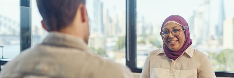 A woman listens to a man talking in a city office setting.