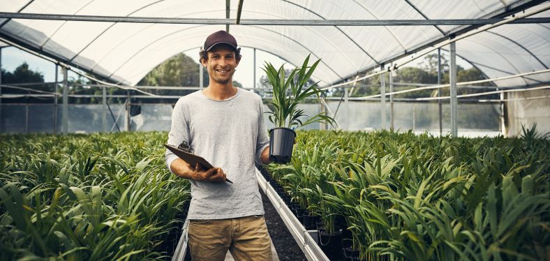 Man holding up a plant inside a growing igloo