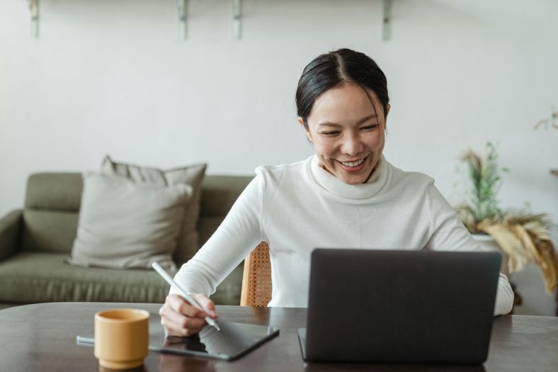 A woman sat at a table with a laptop and tablet