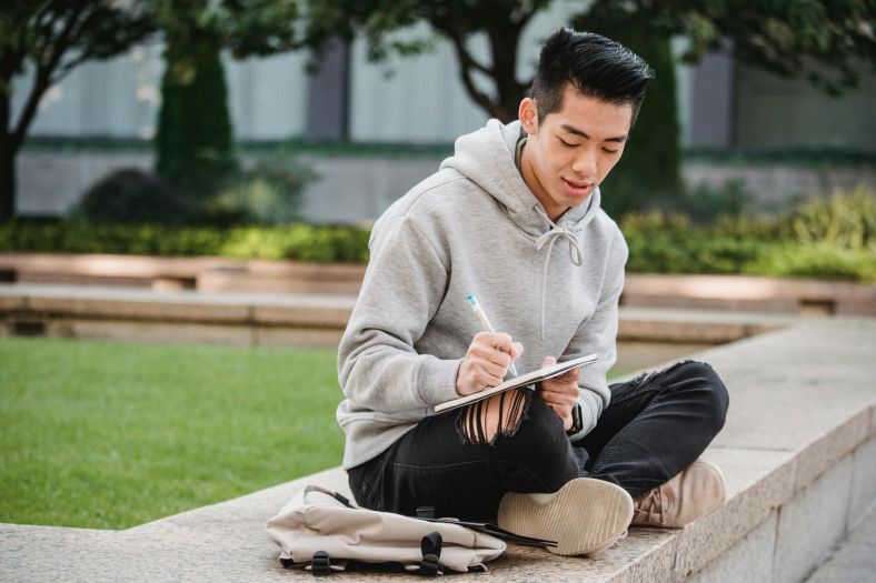 A young man sitting on wall cross-legged.