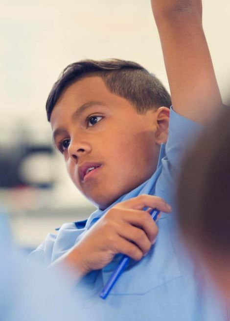 Young Aboriginal school boy in class, putting his hand up to answer a question