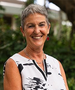 Smiling woman in black and white sleeveless dress in a background of greenery