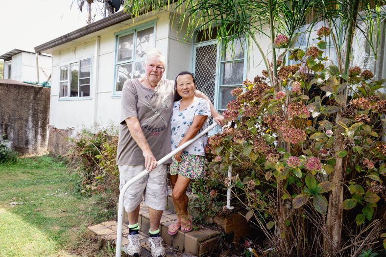 An elder couple outside their house
