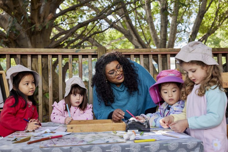 Childcare educator teaching three young children