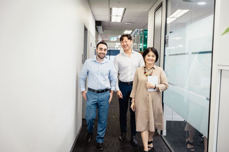 A group of three office workers walking down a corridor