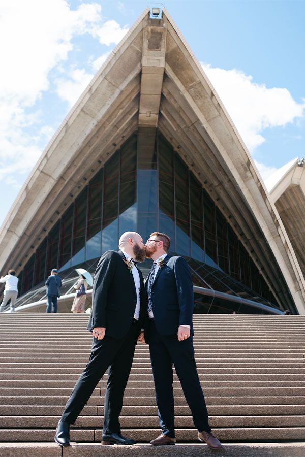 Two grooms share a kiss under the sails of the Sydney Opera House