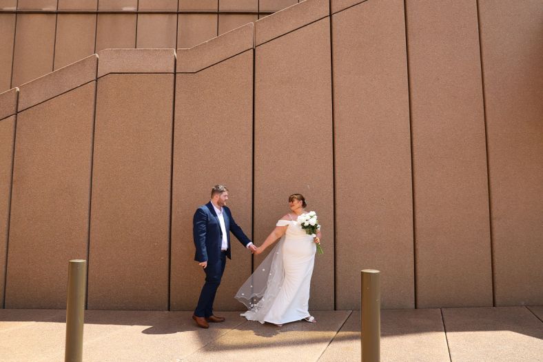 A bride and groom pose on the Opera House forecourt