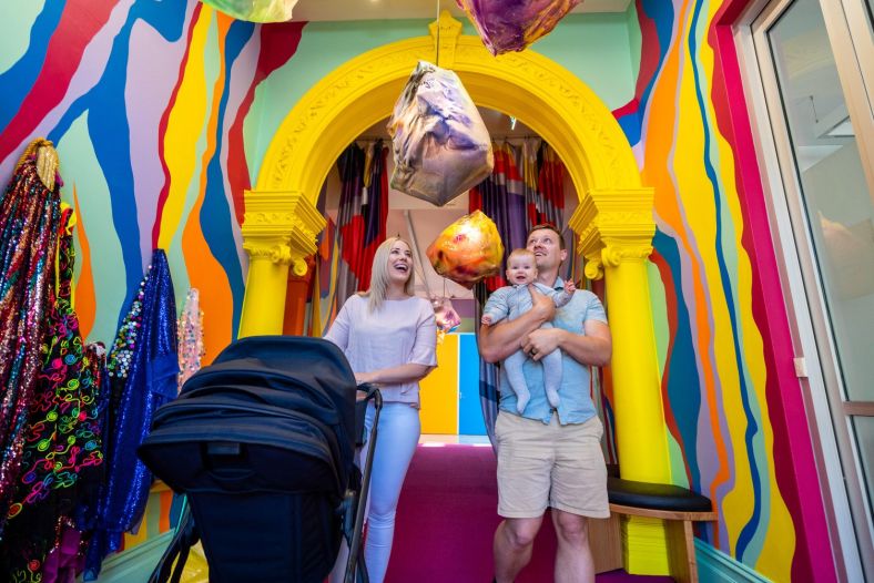 A young family walk through a brightly painted walkway