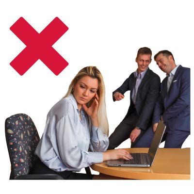 Women at desk working looking away from two men pointing and laughing sad