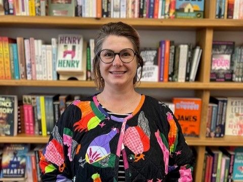 Woman wearing a colourful jacket in front of a book case