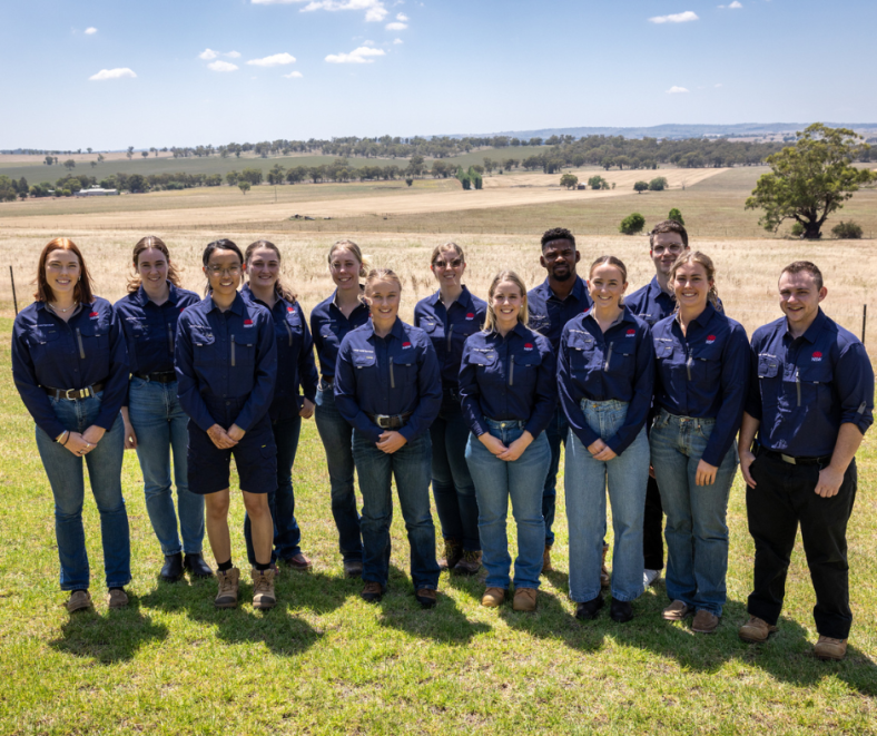 a group of graduates from the LLS graduate program smiling in the sun standing in a rural field facing the camera