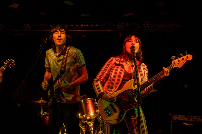 Two people are on stage singing into microphones and playing guitars