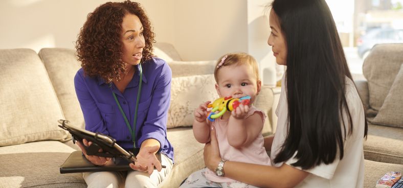 An official worker sitting on a couch with a young mother and her daughter