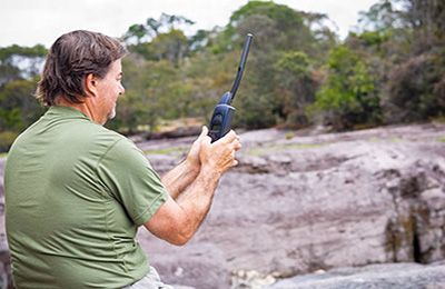 Person in the bush holding a radio.