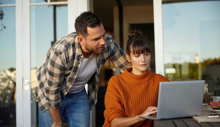 A couple outside looking at a laptop