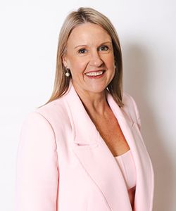 Image of a smiling blond woman in a pink jacket and top.