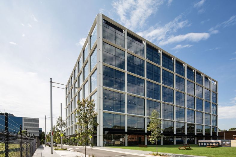 New office building on street with park in front of it.