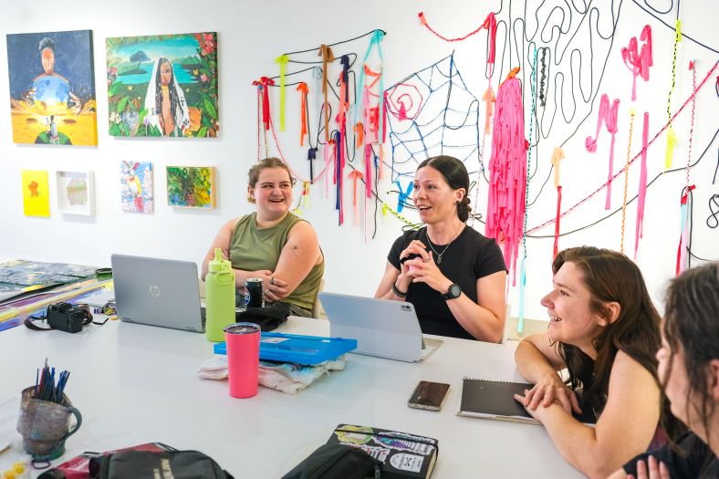 women sit around a table in an artist studio