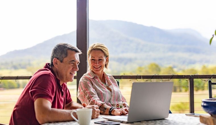 A couple sitting on a balcony using a laptop