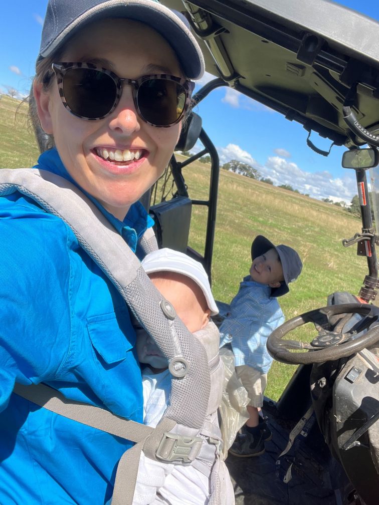 Women wearing baby carrier next to side-by-side vehicle