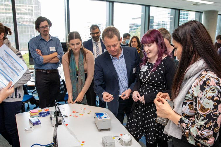 People gathered at the OPENAIR project launch event observe low cost sensing devices.