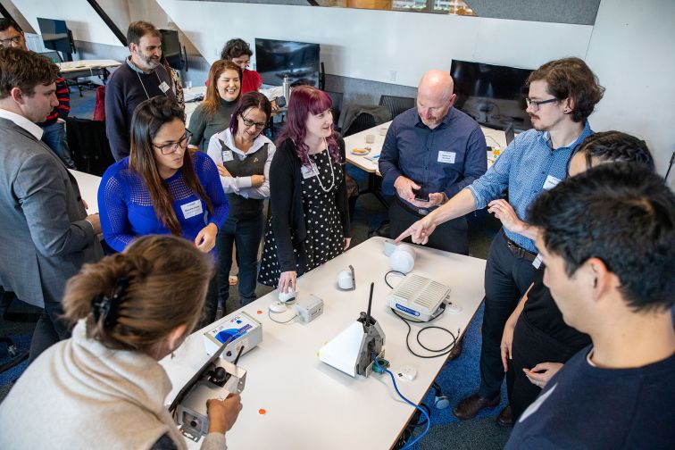 People gathered at the OPENAIR project launch event observe low cost sensing devices.