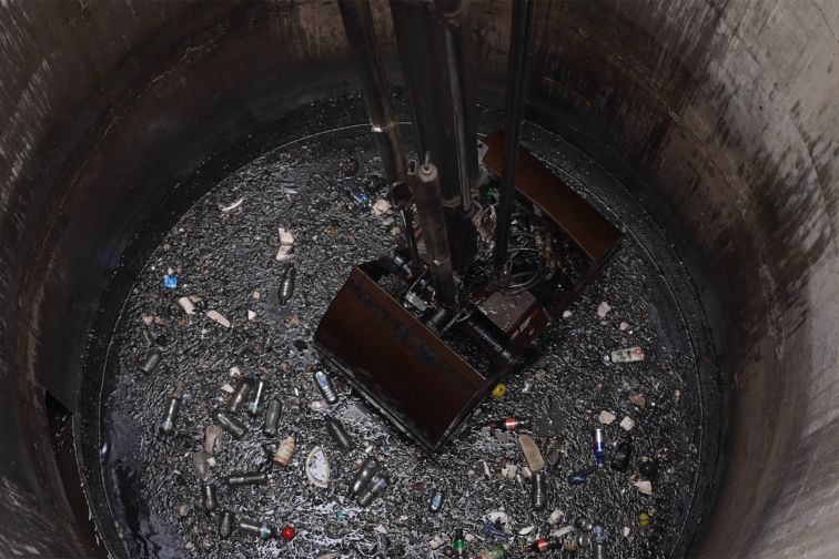 A crane grabs rubbish floating in water out of a gross pollutant trap in Sydney Olympic Park.