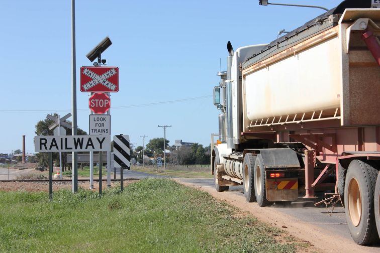 A truck crosses the railway tracks at a level crossing in Narromine, with smart signgage with LED lights installed.