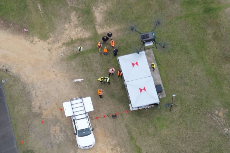 Aerial shot of a drone flying over a car and building