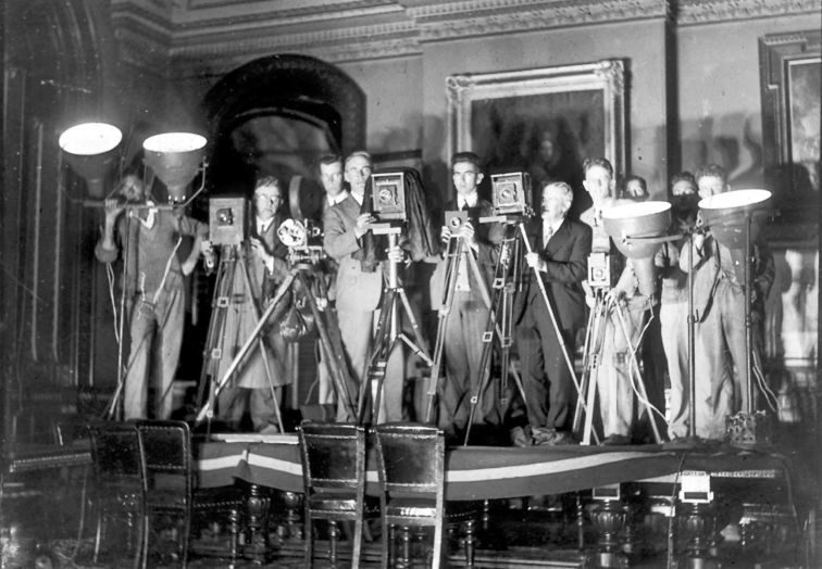 Press photographers and one newsreel man who reported the dismissal of the Lang Government, 31 May 1932, in the Cabinet Room of the NSW Treasury. Photographer Sam Hood asked Treasury officials to allow the press men to stand on the table for a photograph. They only agreed to this after Hood suggested placing a carpet on the table to protect it.