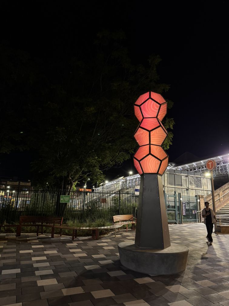 Sculpture lit up at night, outside Homebush Station