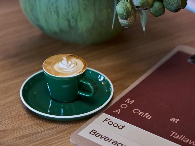 A cup of coffee and a menu from a cafe on a table.