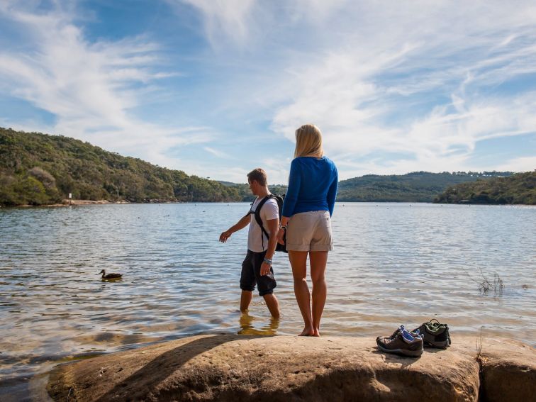 A man and a woman standing on a rock near the Manly Dam