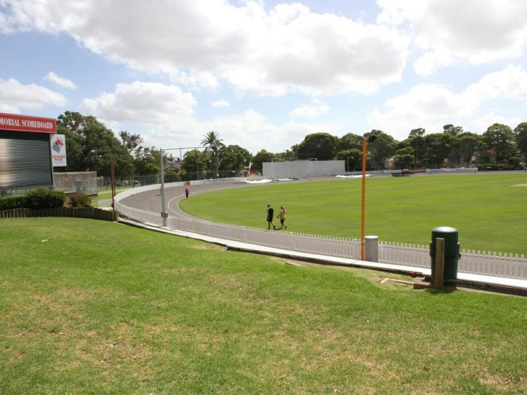 A sunny day at Hurstville Oval where visitors walk along the grass