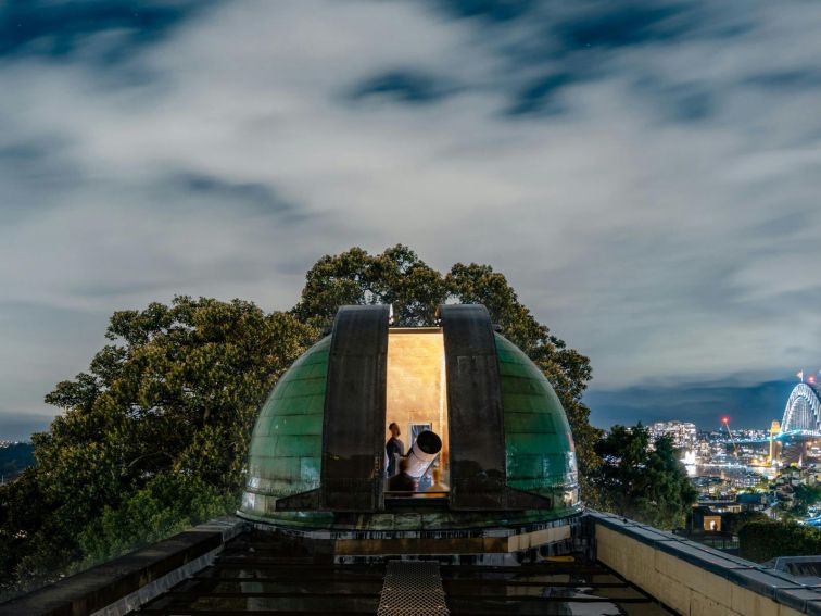 Opened observatory dome with person navigating a telescope.