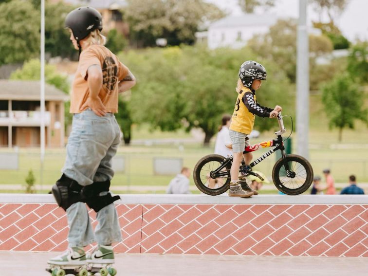 Woman on Roller skates Child on Bike on Opposite sides of the Bowl at Albury Skate Park